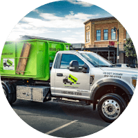 A green junk removal franchise truck on a city street.