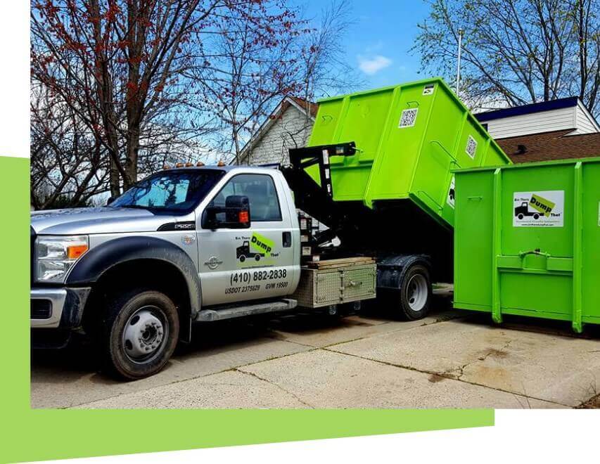 A green dumpster being loaded onto a junk hauling franchise disposal truck.