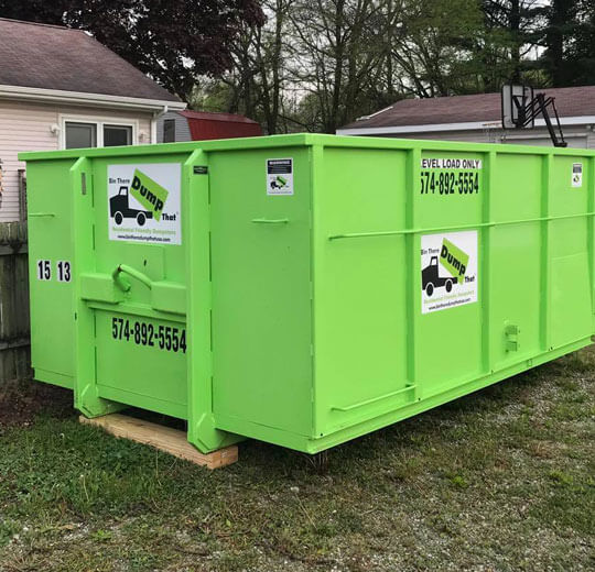 A bright green dumpster rental franchise with company branding and contact information placed on a residential street.